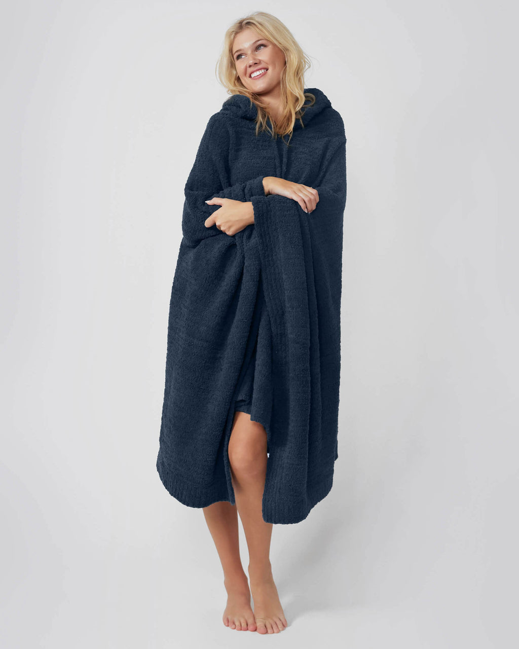 Woman wearing a navy blue hooded poncho against a white background