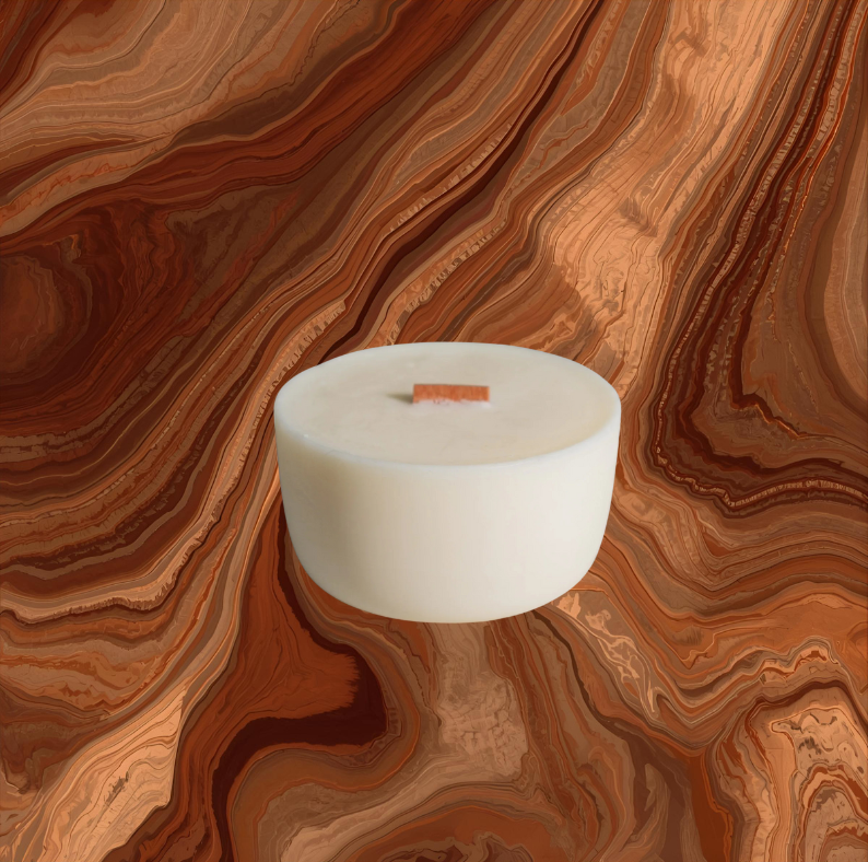 White candle in a glass holder on a brown and orange swirled background